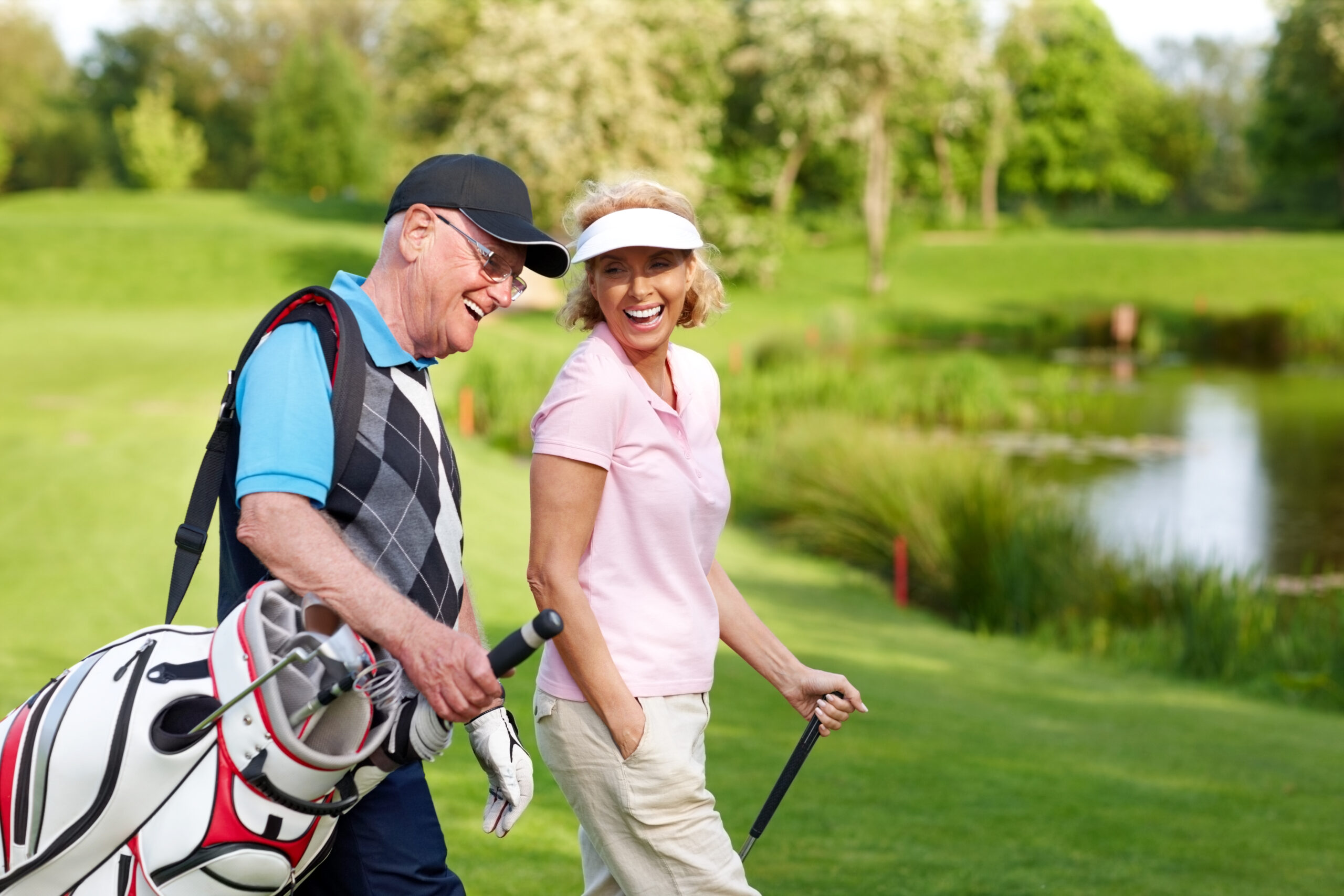 Image of a cheerful mature couple walking on a golf course together