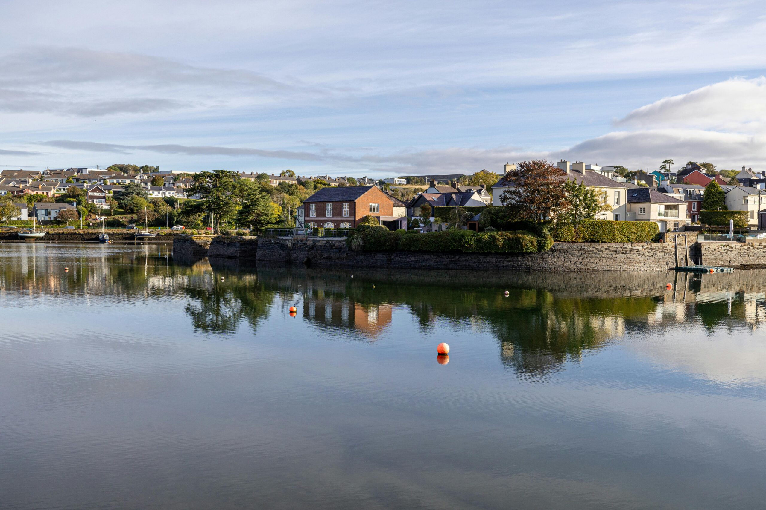 The picturesque fishing village of Kinsale, County Cork, Ireland, with its brightly colored buildings, boats bobbing in the harbor, and a stunning coastal landscape. 