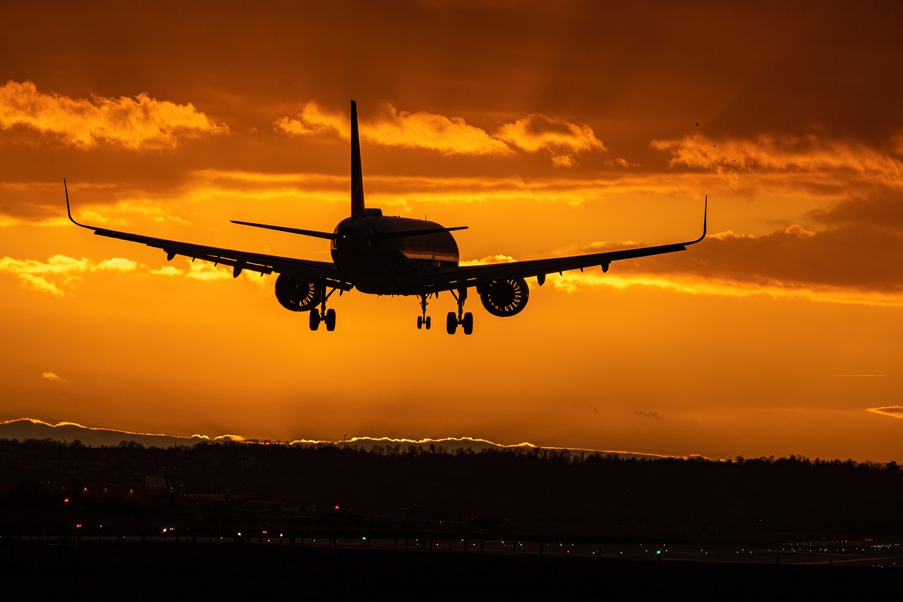 A commercial airplane soars through the sky at sunset